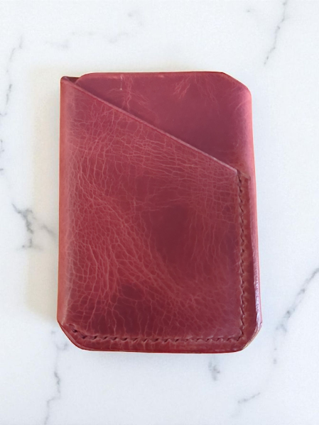 Dark pink pull up leather wallet on a marble surface
