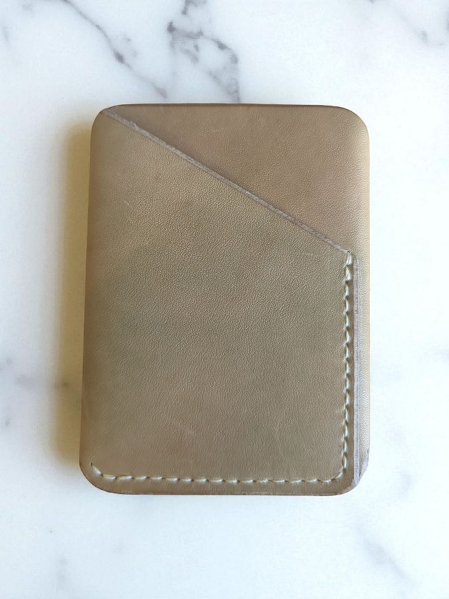 Tan with green hues leather wallet on a marble surface