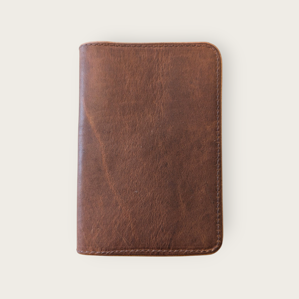 Brown leather passport cover on a light beige background